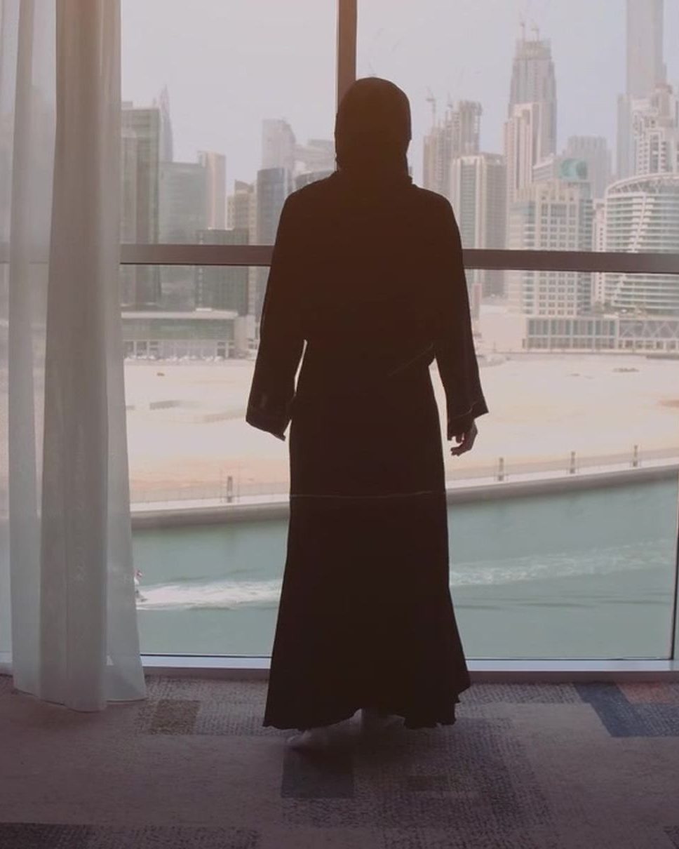 A woman in an abaya looking out over the city