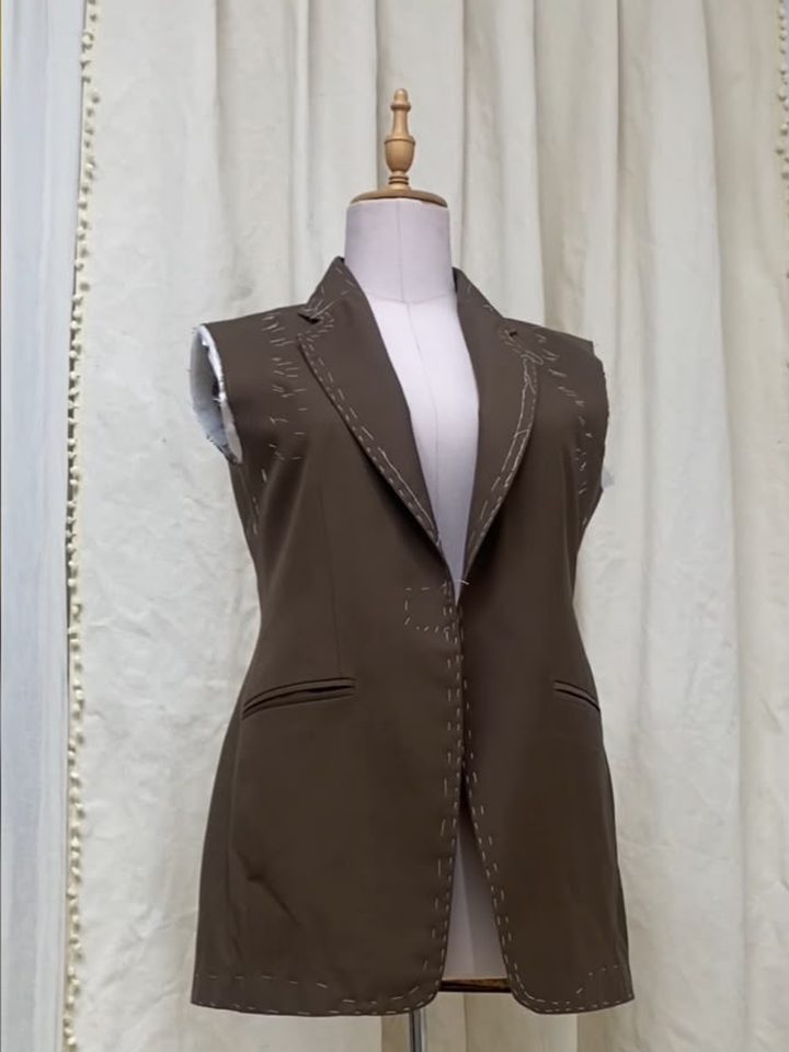 Olive waistcoat on a dress form with visible basting stitches